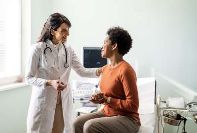 Doctor comforting a seated patient in a bright exam room.