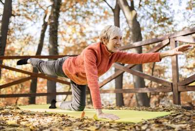 Woman doing yoga on a mat in an autumn forest.