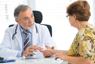 Doctor examining a patient's hand compassionately in an office setting.