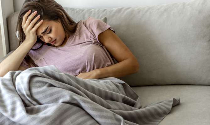 Young woman with stomach pain in need of urgent care in St. Louis, MO