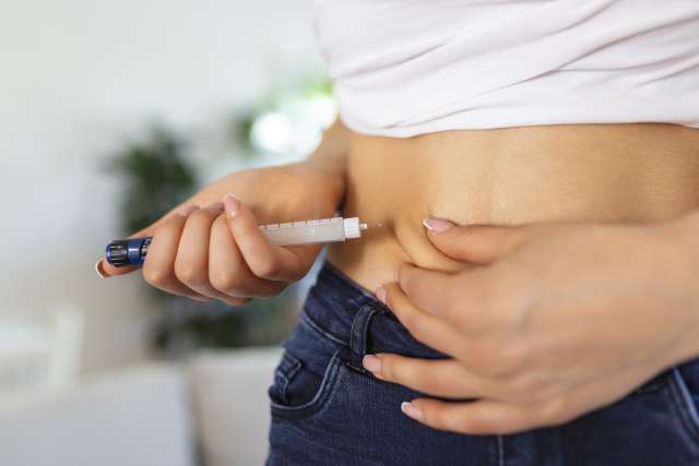 Person injecting insulin into their abdomen.