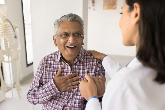 Doctor and elderly man smiling in a medical office.