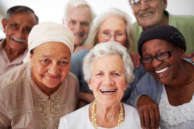 Group of smiling elderly friends wearing colorful clothing.